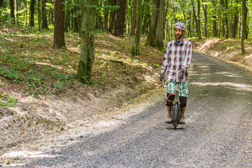 Obraz premium Men learns to ride a monowheel on a rural country road.