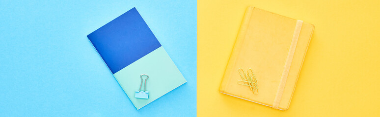 Panoramic shot of blue and yellow notepads on bicolor background