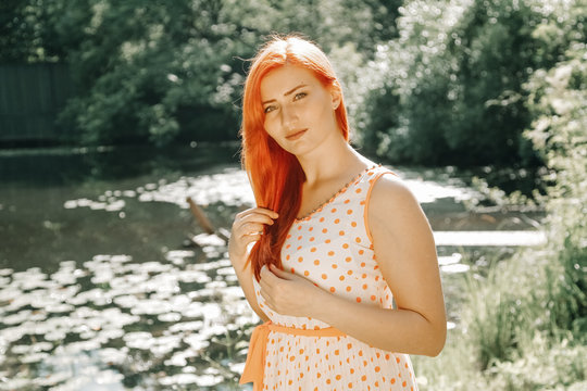 cute redheaded girl walking in the summer hot city park