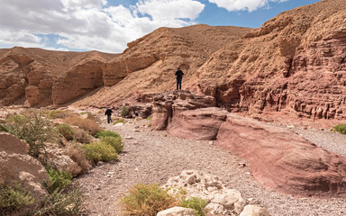 tourists enjoying the red sandstone boulders on a hike in the red canyon near eilat in israel