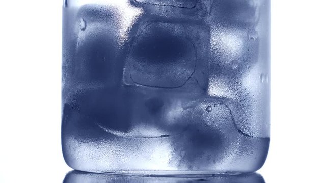 Ice cubes melting in drinking glass. Nobody. Blue tone