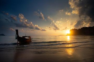 Amazing sunset with longtail boats silhouette at Railay beach, Thailand.