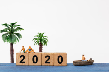 Miniature people wearing swimsuit relaxing on sitting on wooden block number 2020  , Happy new year concept