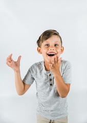 Little boy with autism standing on a white background feeling happy and smiling with his arms raised