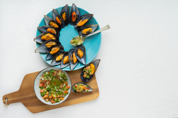 Steamed mussels with onion vinaigrette, tomato and cilantro on white background. Copy space