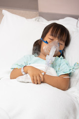 Little Asian girl is sick in a bed with an oxygen mask in hospital