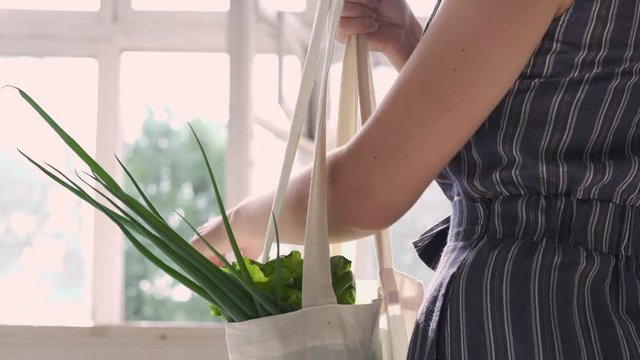 Zero waste home and eco bag. Eco Shopping. Reusable grocery bags with fruits and vegetables on the kitchen on wooden table. Slow motion