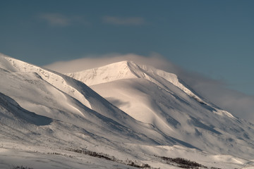 Fototapeta na wymiar Snow covered hills along Teusajaure valley in Lapland Sweden in beautiful mist, sun, blue sky