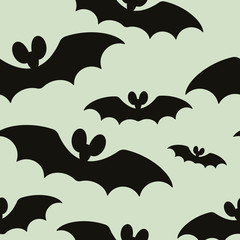 The seamless pattern with the silhouettes of bats is on a gray background.