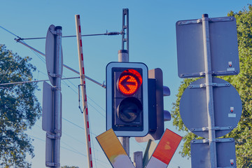 Railroad crossing with warning sign and lights with a gravel road 