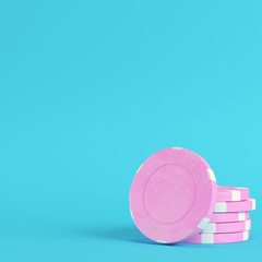 Pink casino chips on bright blue background in pastel colors