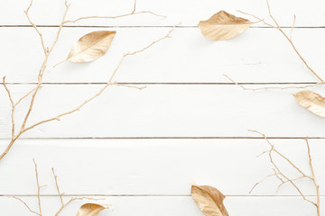 Autumn composition. Frame made of fall leaves and golden decorations on wooden white background. Flat lay, top view, overhead. Nordic, hygge, cozy home desk table concept.