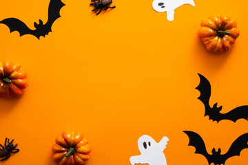 Happy halloween holiday concept. Halloween decorations, pumpkins, bats, ghosts, on orange background. Halloween party greeting card mockup with copy space. Flat lay, top view, overhead.