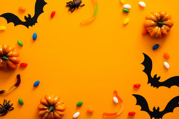 Obraz na płótnie Canvas Happy halloween holiday concept. Halloween decorations, pumpkins, bats, candy, bugs on orange background. Halloween party greeting card mockup with copy space. Flat lay, top view, overhead.