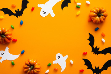 Obraz na płótnie Canvas Happy halloween holiday concept. Halloween decorations, pumpkins, bats, candy, ghosts, bugs on orange background. Halloween party greeting card mockup with copy space. Flat lay, top view, overhead.