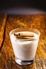 Delicious rice pudding with cinnamon in bowl on wooden background.