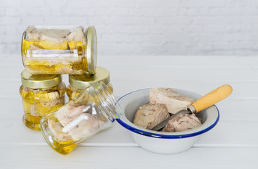 Preparation of canned tuna in glass jars on white background.