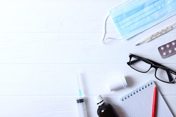 Doctor's desk top view. Set of different doctor accessories on a colored background. Pills, glasses, stethoscope and notebook.