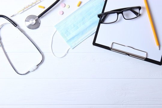 Doctor's desk top view. Set of different doctor accessories on a colored background. Pills, glasses, stethoscope and notebook.