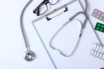 Doctor's desk top view. Set of different doctor accessories on a colored background. Pills, glasses, stethoscope and notebook.