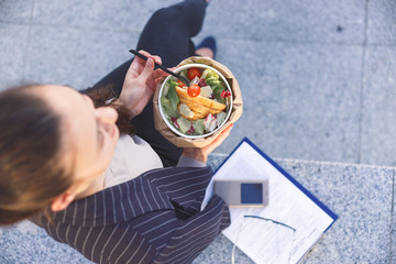 Office worker eating salad outdoor. Top view