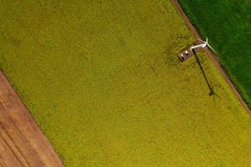 Aerial top-down view of farm fields with wind turbine during hot sunny day