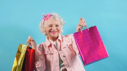 Old stylish lady rejoicing at bargain, new trendy clothes. Big, huge sale, Black Friday. Isolated blue background. Free time