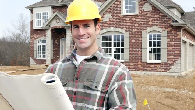 Construction: Smiling Home Builder Reads Plans And Looks To Camera