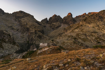 Amazing landscape of The Scary lake during warm summer sunset with small stone shelter, Rila mountain national park, Bulgaria