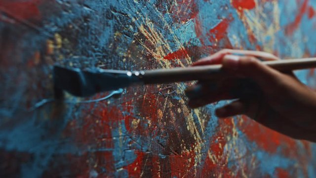 Close-up Shot of Female Artist Hand, Holding Paint Brush and Drawing Painting with Blue Paint. Colorful, Emotional Oil Painting. Contemporary Painter Creating Modern Abstract Piece of Fine Art