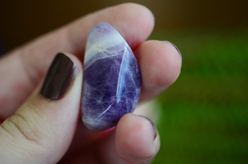 Beautiful tumbled Amethyst, lots of rainbows. Beautiful polished amethyst tower. Bright Quartz crystal, healing crystal being held in hand. Woman holding amethyst tower, natural lighting, reiki energy