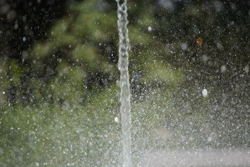 water jet and spray around. cooling on a hot day at the fountain or pond on blurred nature background.