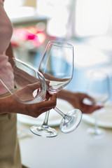 Midsection of young waitress holding wineglasses at restaurant