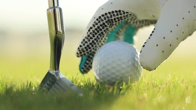 Hand in glove placing golf ball on tee