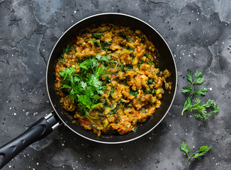 Eggplant spinach vegetarian curry in a pan on a dark background, top view. Indian cuisine