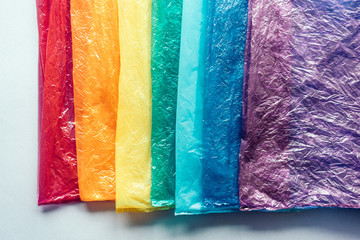 Plastic bags in a row by the colors of the rainbow on gray background. The concept of recyclable household and industrial waste.