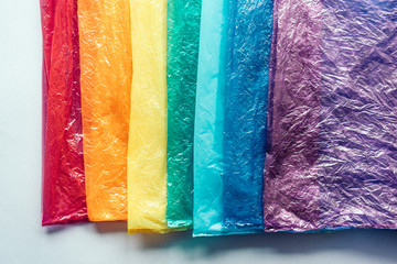Naklejka premium Plastic bags in a row by the colors of the rainbow on gray background. The concept of recyclable household and industrial waste.