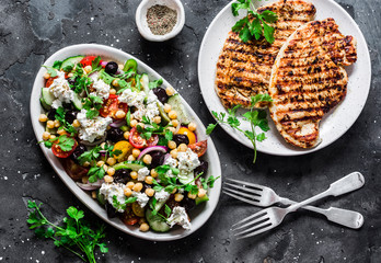 Mediterranean style lunch table - Greek chickpeas salad and pork chops on dark background, top view