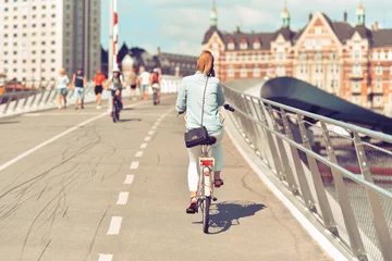 Foto op Aluminium Woman cyclist in casual wear rides on bicycle by city. Photo in vintage style. © Oleksandr