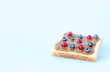 Toast with peanut butter and berries on a blue background.