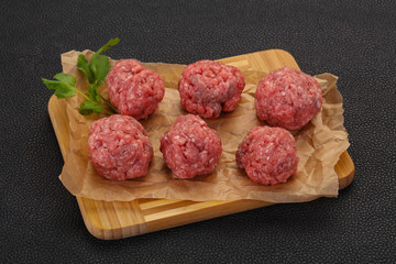 Raw meatball over wooden background
