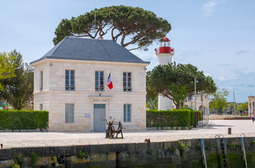 Old port office or Bureau du Port and lighthouse in historical harbor of La Rochelle, France