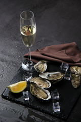 Opened oysters, ice and lemon on stone table. Oyster dinner with champagne in restaurant. Vertical