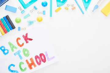 Top view of paper with back to school text near school supplies isolated on white