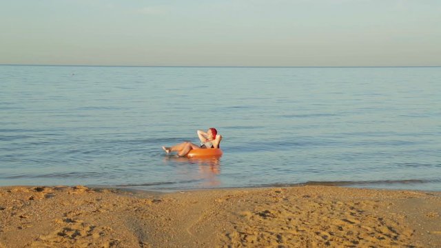 A woman with red hair in a bathing suit on the sea wave