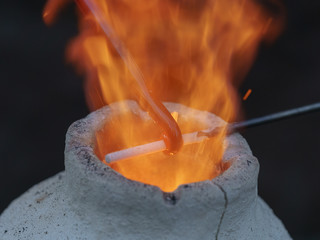 Photography of the process of making beads in the workshop. Man glassblower make handmade products under burner. Ancient Slavic technique depends on bellows fanning.