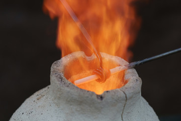 Photography of the process of making beads in the workshop. Man glassblower make handmade products...
