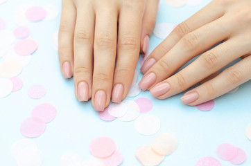 Nude female manicure on a blue background.