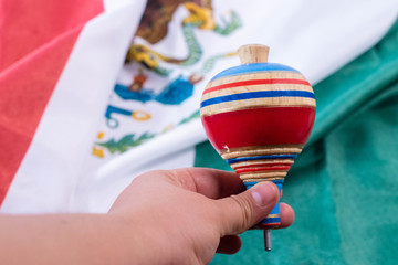 Woman had holding a colorful wooden spin with a mexican flag as background
