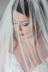 Morning of the bride. Beautiful young bride with wedding makeup and hairstyle in bedroom. Beautiful...
